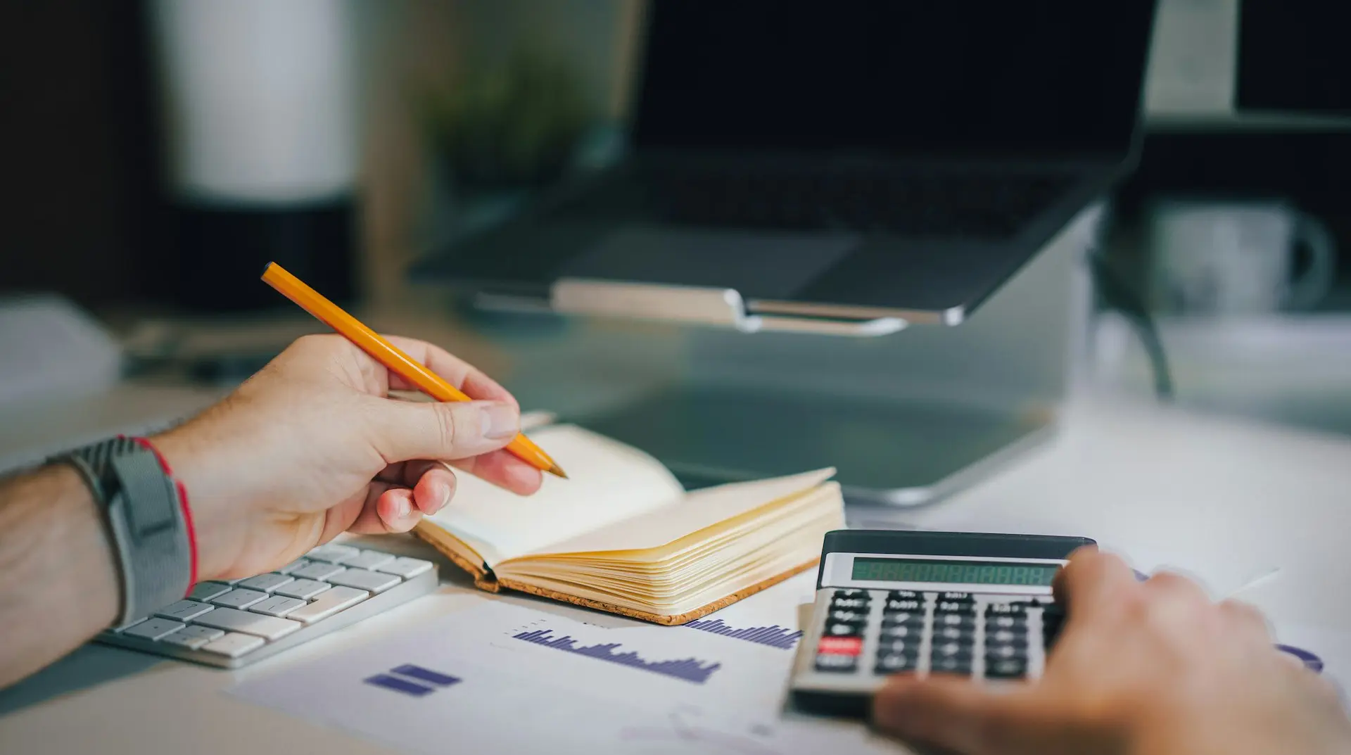 a person sitting at a desk with a calculator and a notebook